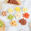 A collection of realistic resin fake corn miniatures in various colors and shapes arranged on a white marble surface.