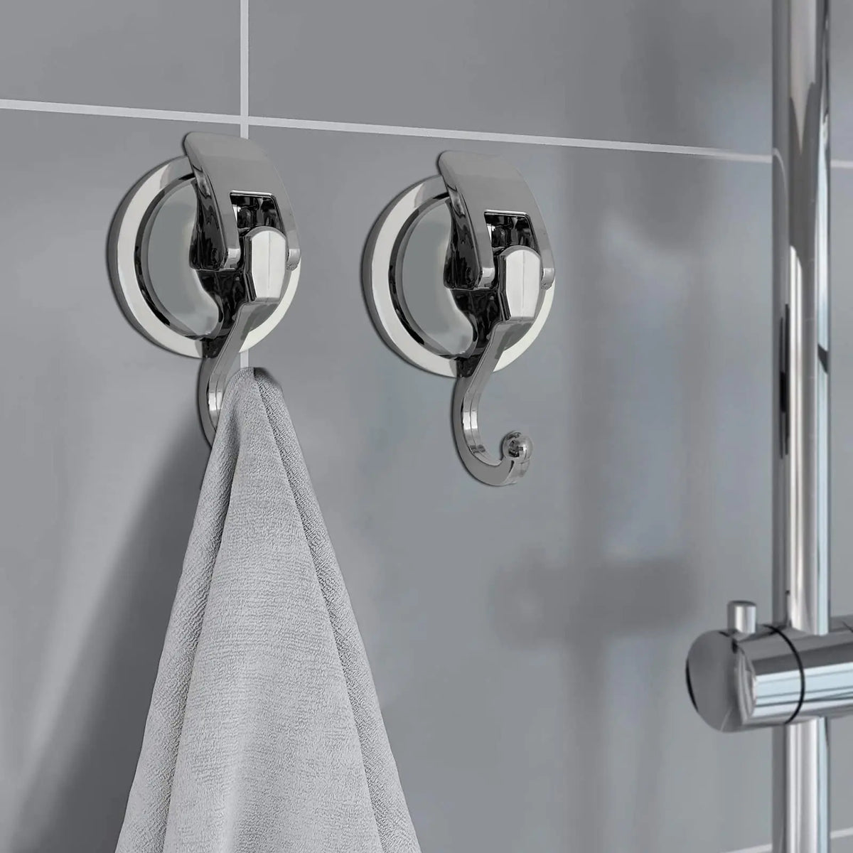 Silver suction cup hooks mounted on a shower rod, used for hanging towels.