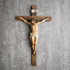 A hand-painted resin cross statue depicting Jesus Christ crucified on a wooden beam.