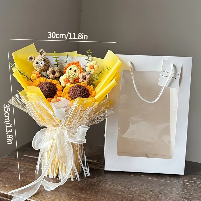 A bouquet of handmade crochet flowers featuring a teddy bear and various blooms, wrapped in yellow paper and tied with sheer 