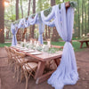 Tissu de mousseline bleu clair drapé, utilisé pour créer un fond floral pour une table d'événement en extérieur.