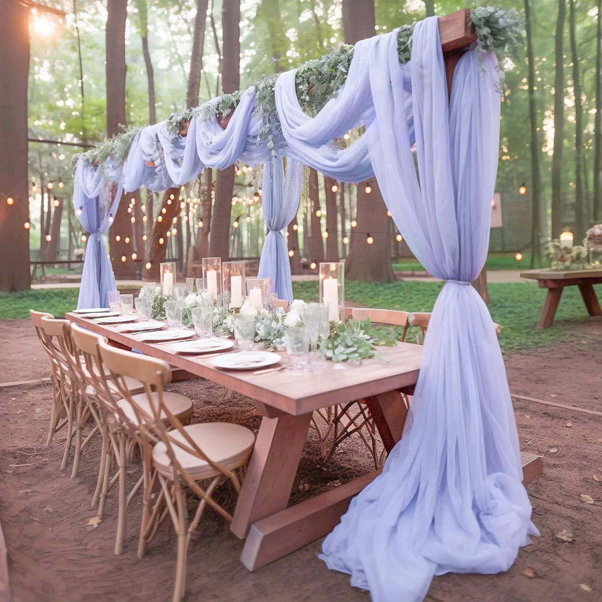Tissu de mousseline bleu clair drapé, utilisé pour créer un fond floral pour une table d'événement en extérieur.