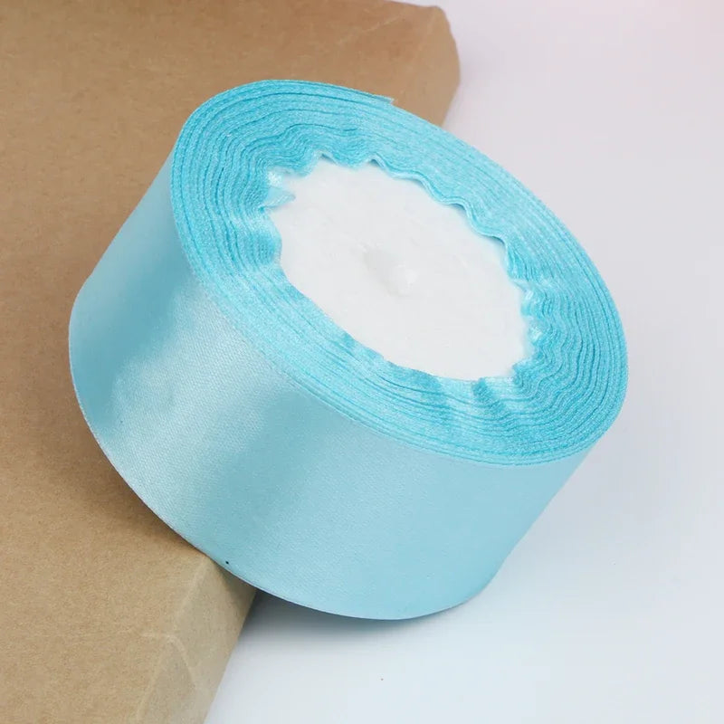 Roll of light blue satin ribbon with white filling for crafts and gift wrapping