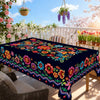 A vibrant Mexican carnival printed tablecloth displayed on a wooden table outdoors.
