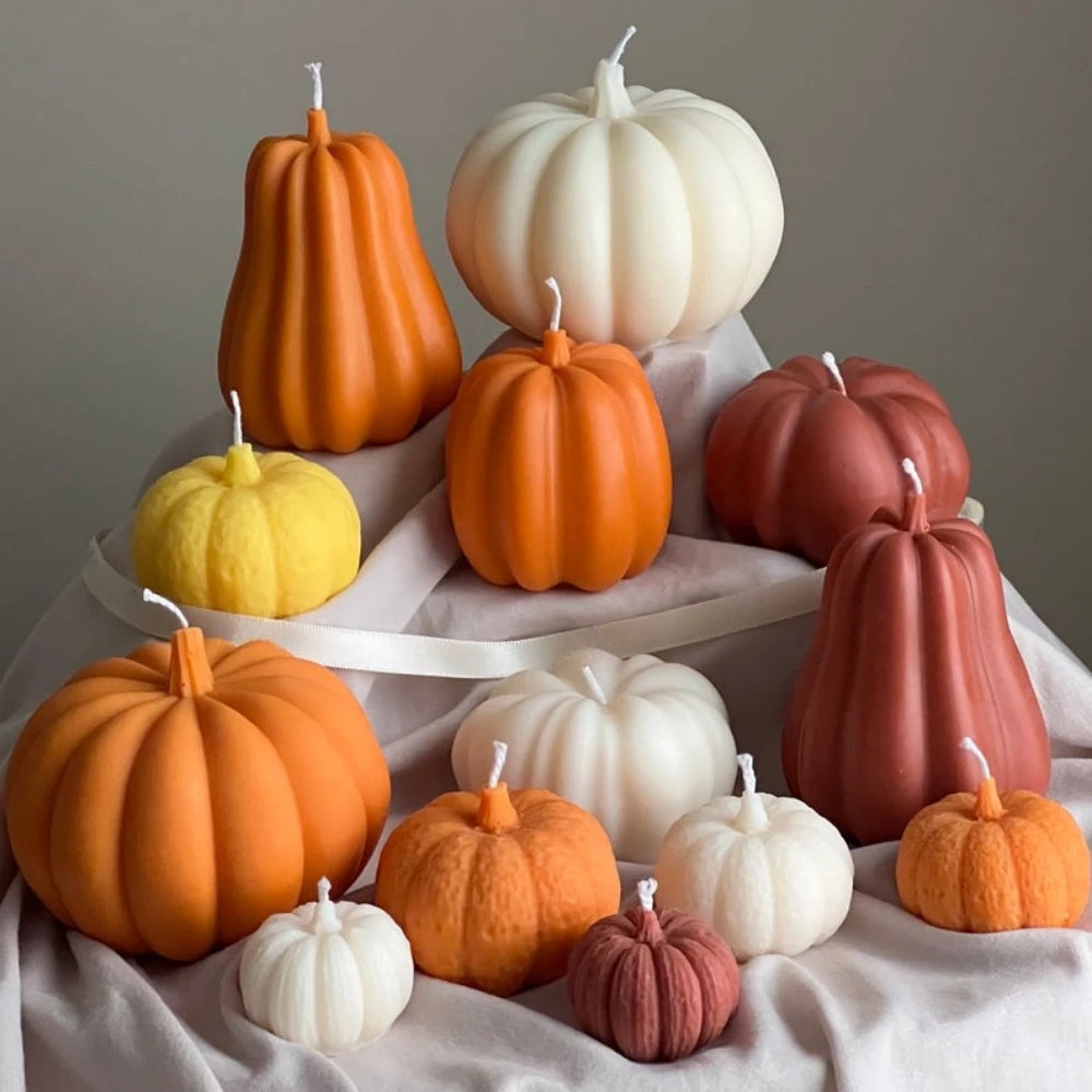 A collection of various orange, white, and pink silicone pumpkin molds arranged on a white cloth.