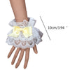 White ruffled lace wrist cuffs with a yellow bow accent shown on a hand.