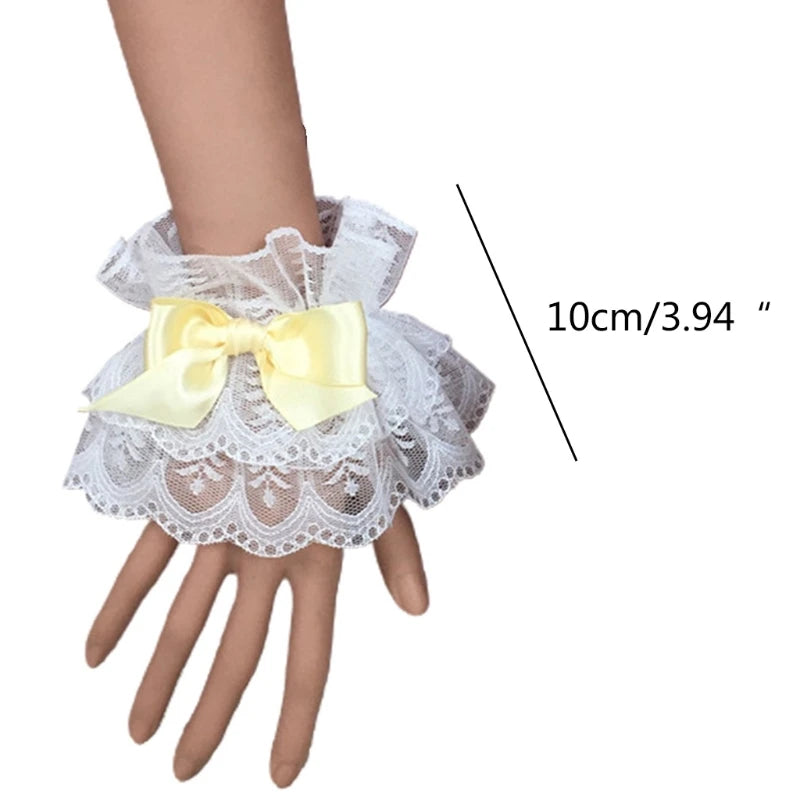White ruffled lace wrist cuffs with a yellow bow accent shown on a hand.