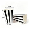 A white paper snack box with black diagonal stripes, shown next to a measurement guide.