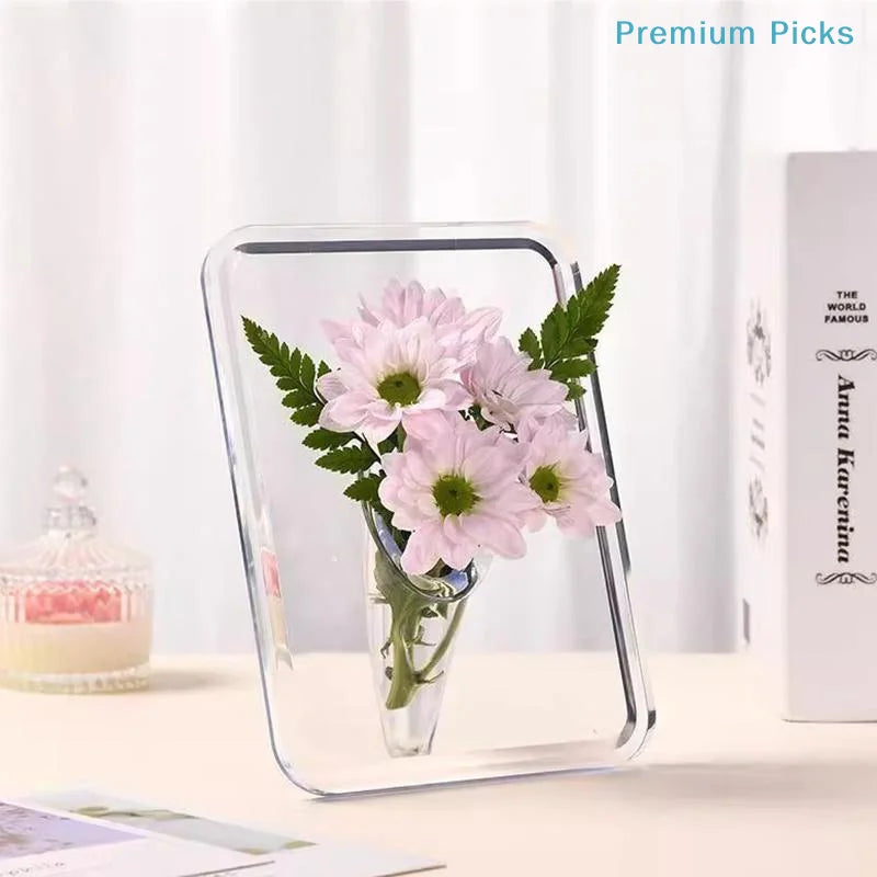 A clear acrylic frame holds a pink flower arrangement in a glass vase on a white surface.