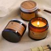 Two jars of Aroma Sensation scented candles are displayed on a white towel with a wooden matchstick.