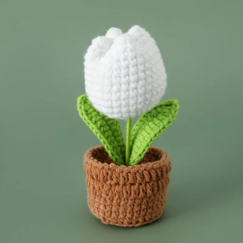Handcrafted white crochet tulip flower with green leaves growing in a brown crocheted pot