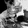 A hand holds a glass of liquid, causing splashes, in a black and white photograph.