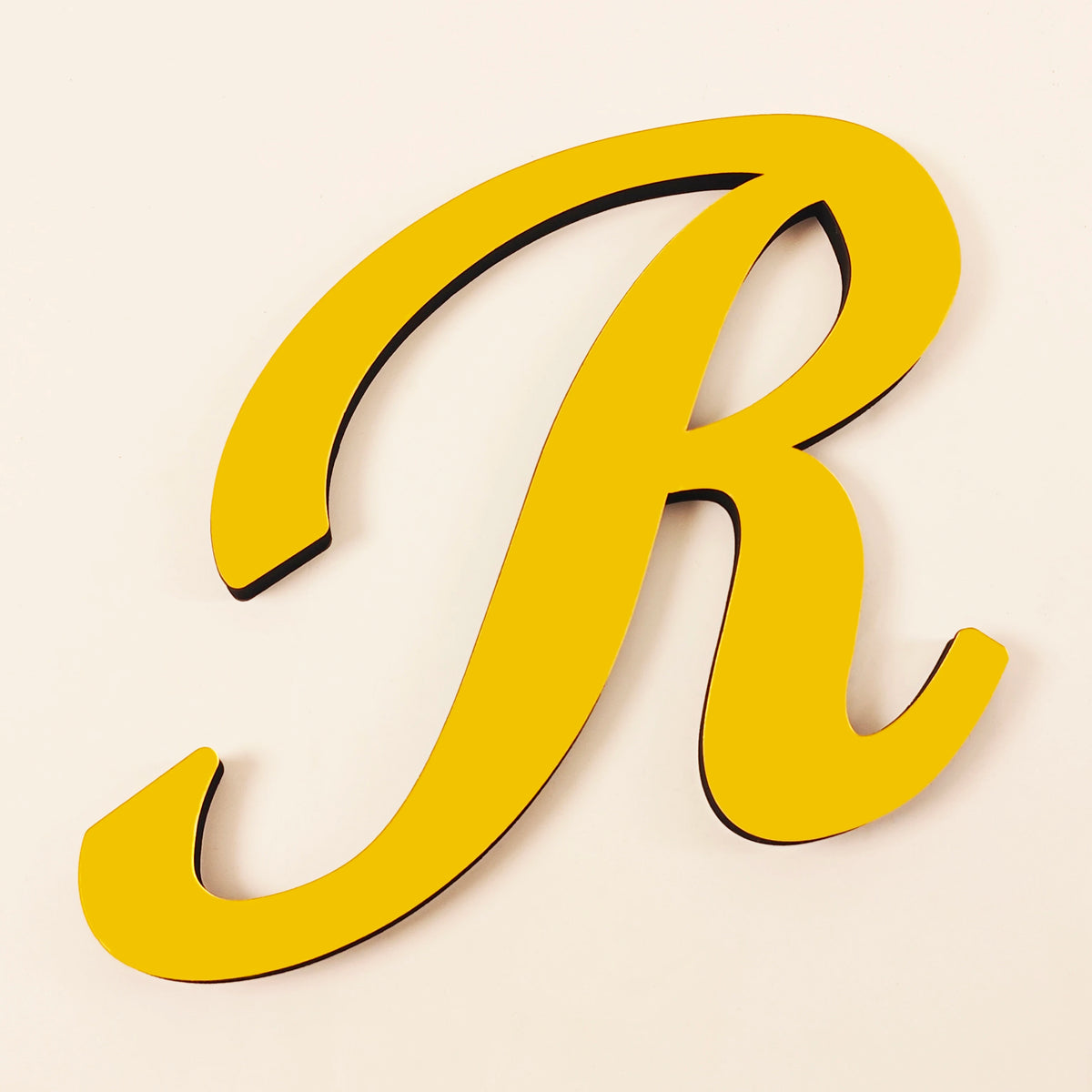 A gold 3D acrylic letter R wall sticker with a shadow effect.