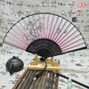 An elegant vintage Chinese folding hand fan with pink and black accents rests on a bamboo tray.
