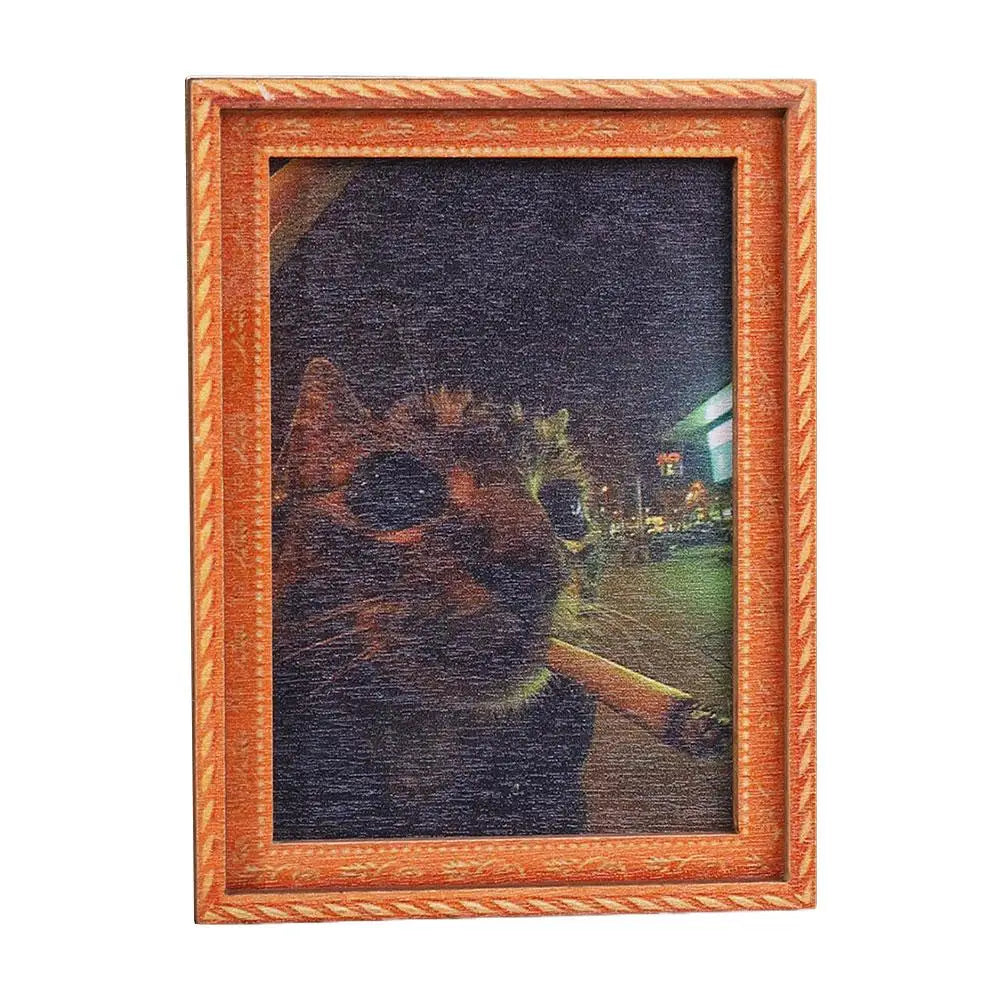 A framed photograph of a cat's face with glowing eyes and a blurred background.