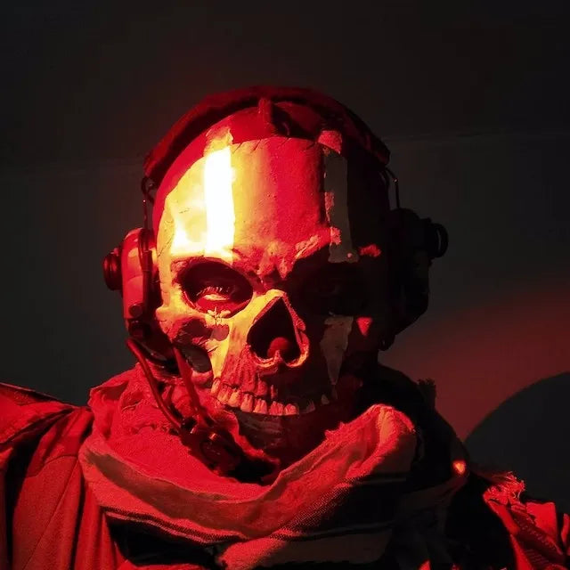 Primer plano de una persona usando una máscara facial táctica de silicona que parece un cráneo, iluminada por luz roja.