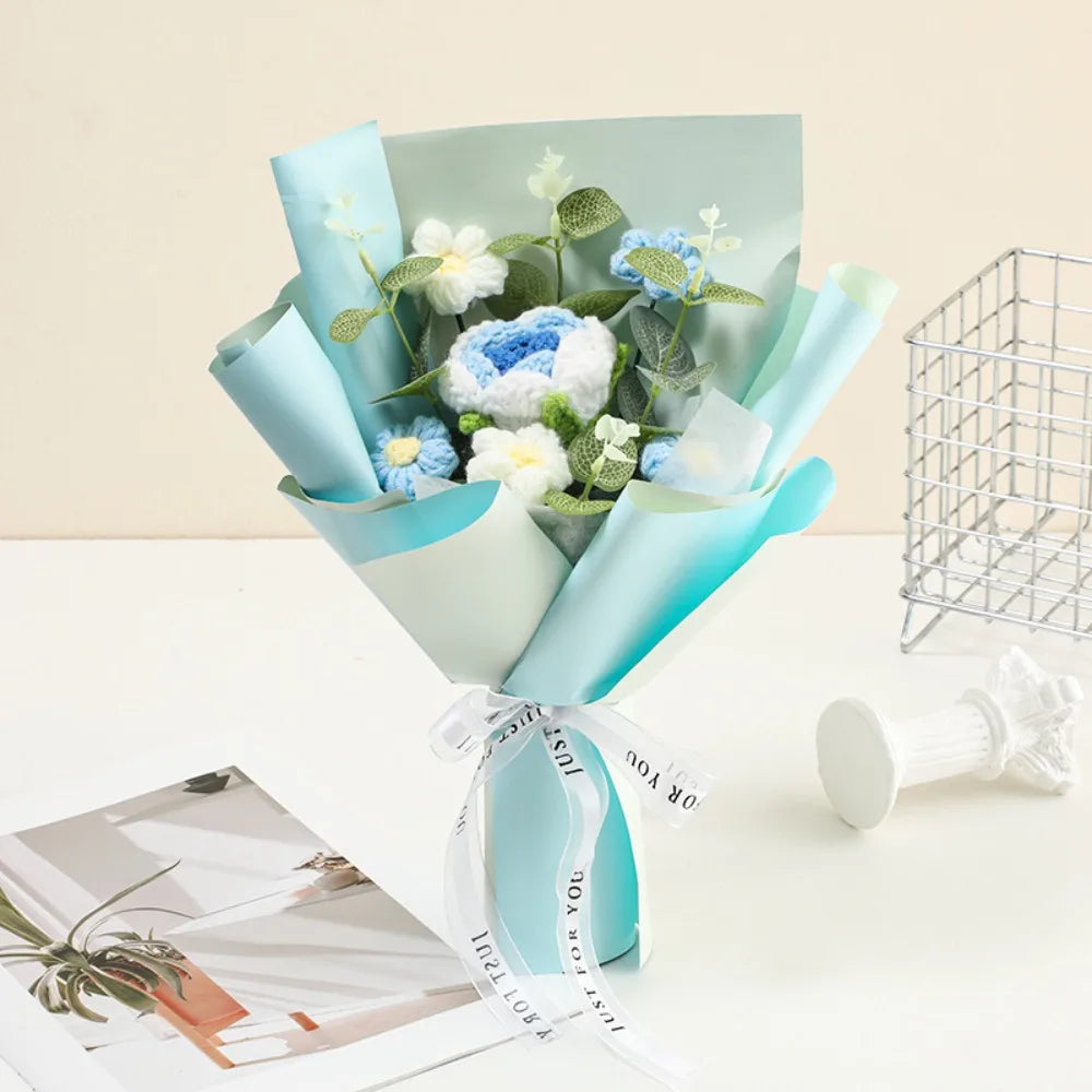 A bouquet of handmade crochet rose flowers in light blue and white, wrapped in pale blue paper.
