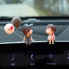 A set of cute couple balloon car ornaments featuring a boy and a girl figurine on a black surface.