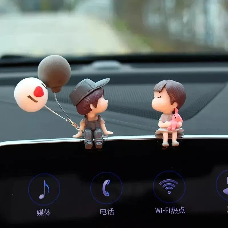 A set of cute couple balloon car ornaments featuring a boy and a girl figurine on a black surface.