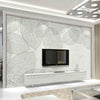 A modern interior featuring a large wall panel with a white leaf pattern and a mounted television.
