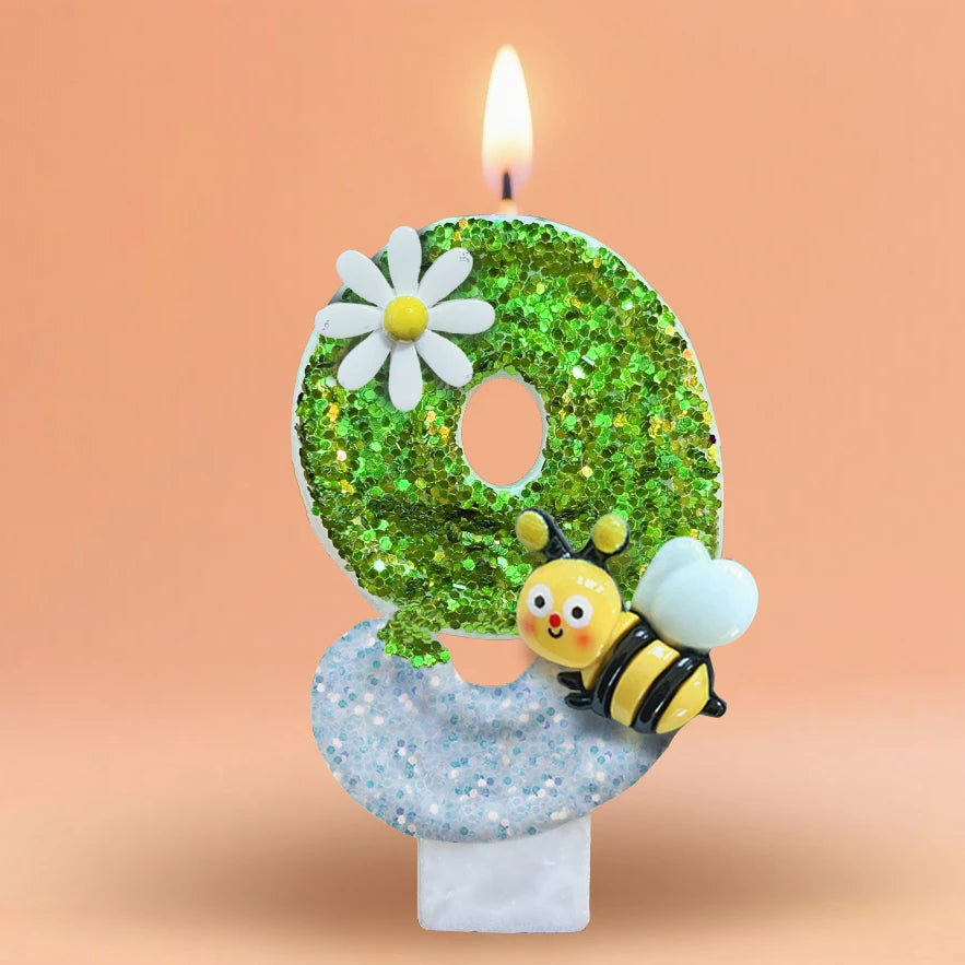 A green glitter number eight candle decorated with a white daisy and a bee, set on a white base.