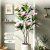 A tall artificial magnolia tree with pink and white silk flowers placed in a white pot indoors.