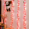 Pink sakura flower garland lights hanging vertically against a white wall