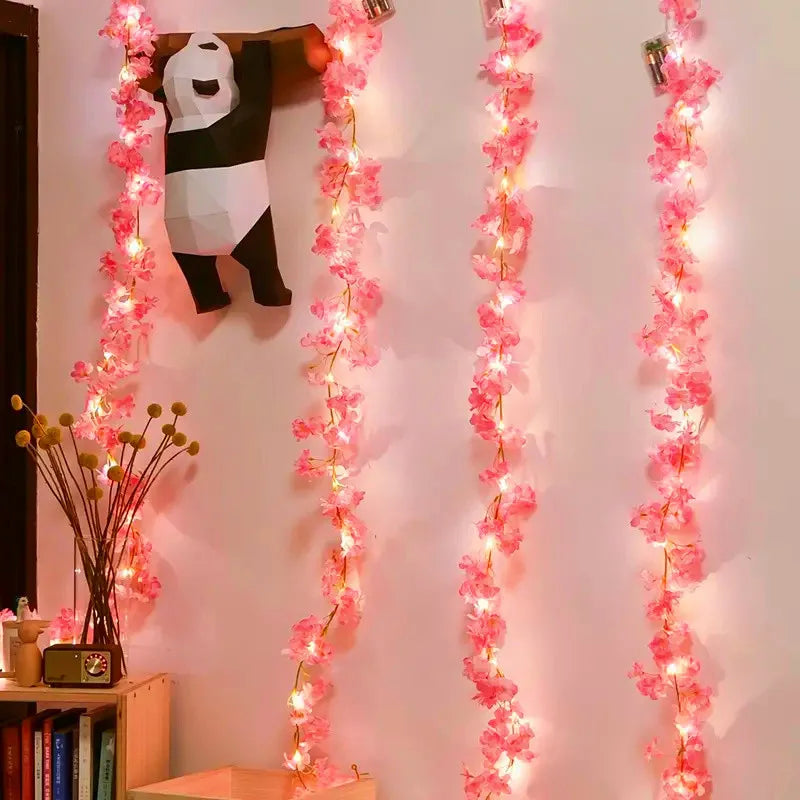 Pink sakura flower garland lights hanging vertically against a white wall