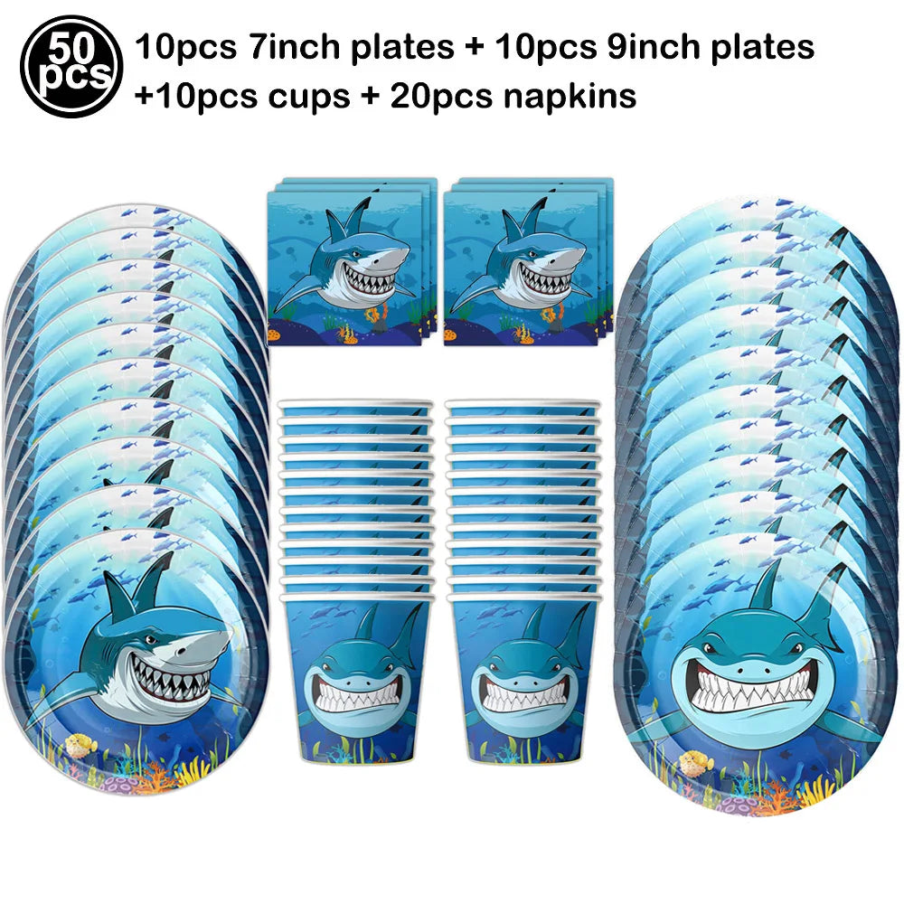 A set of blue shark foil balloons and plates including 7 inch and 9 inch plates, cups, and napkins for an ocean-themed party.