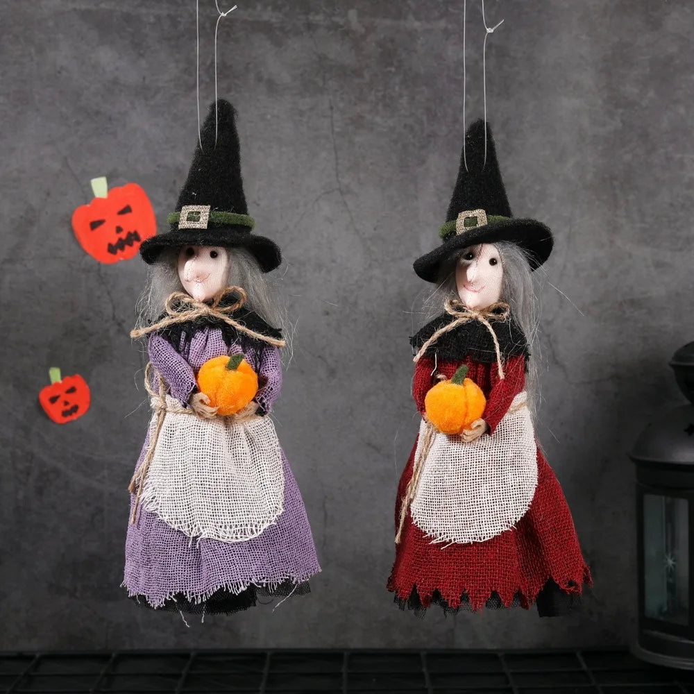 A pair of witch ornaments featuring a black pointed hat, gray hair, and harvest-themed clothing in purple and red.
