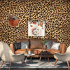 A living room featuring a brown leather sofa and armchairs against a leopard print wallpaper.