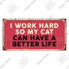 A rustic red wooden sign with white text that reads I work hard so my cat can have a better life