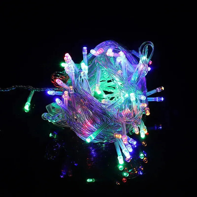 Un paquete de luces LED de hadas multicolores brillantes creando una masa brillante y enredada contra un fondo oscuro.