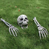 A realistic skull with skeletal hands lying in green grass for Halloween lawn decor.