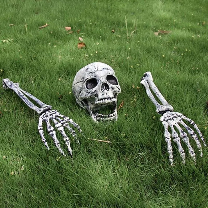 A realistic skull with skeletal hands lying in green grass for Halloween lawn decor.