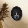 Black framed wall art featuring a lit candle held by hands against a dark background