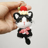 Handcrafted crochet cat keychain pendant with black and white fur and a red bow