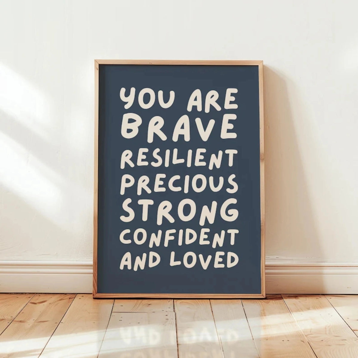 A framed canvas print with white text on a dark blue background that reads You are brave resilient precious strong confident 