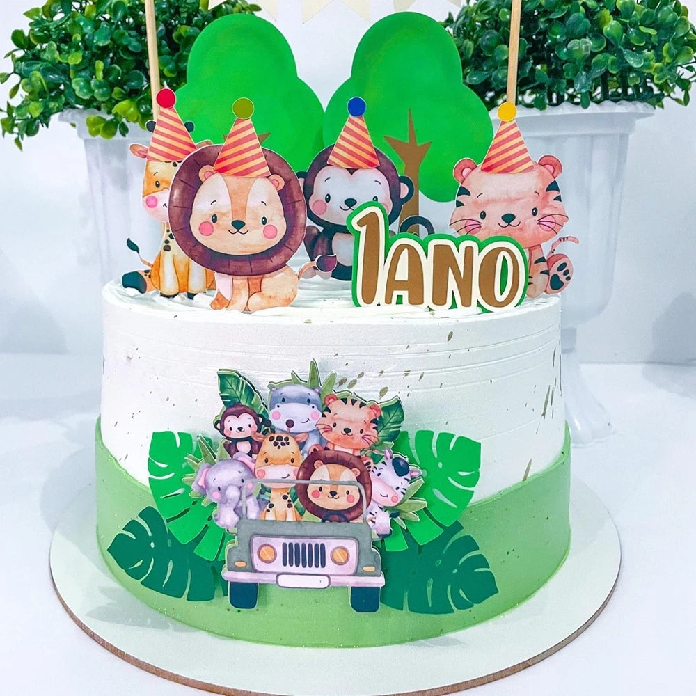 A white cake decorated with green foliage and animal toppers, including a lion, panda, and fox, for a children's party.