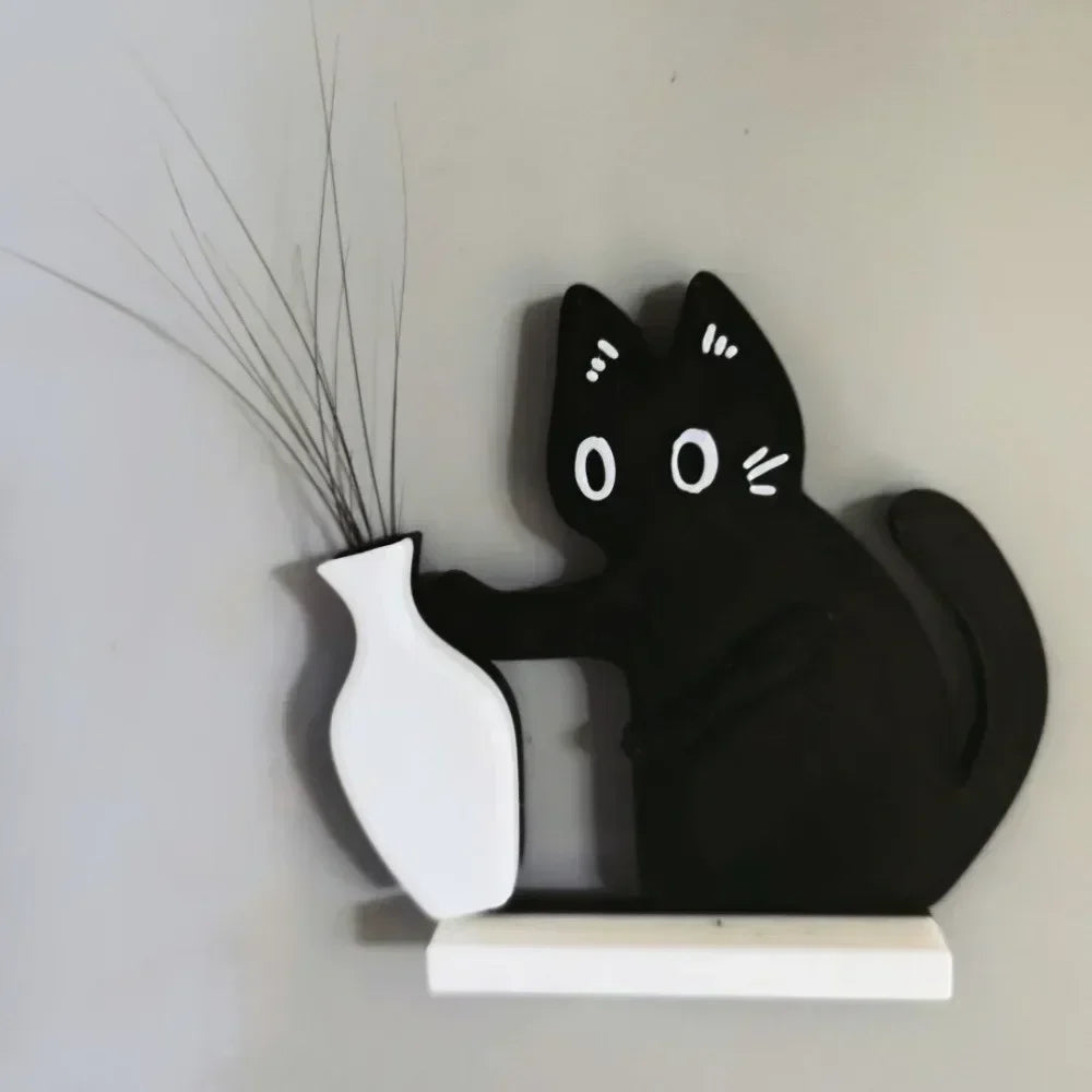 Black acrylic cat figurine with long whiskers and a white vase on a light gray wall.