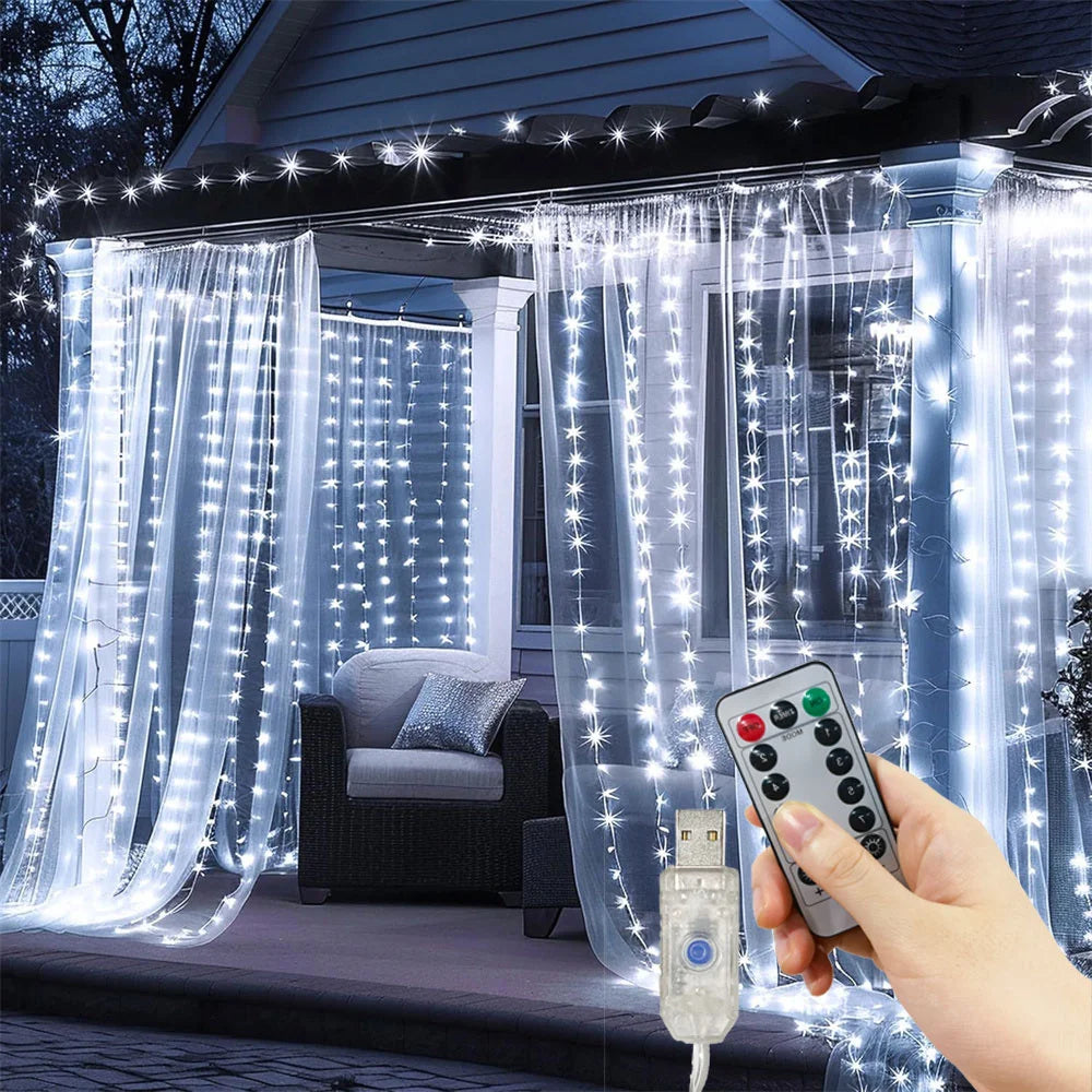 A hand holds a remote control for LED curtain fairy lights illuminating sheer curtains on a window.