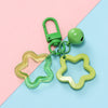 A green padlock charm and a yellow star charm pendant keychain displayed on a pink and blue background.