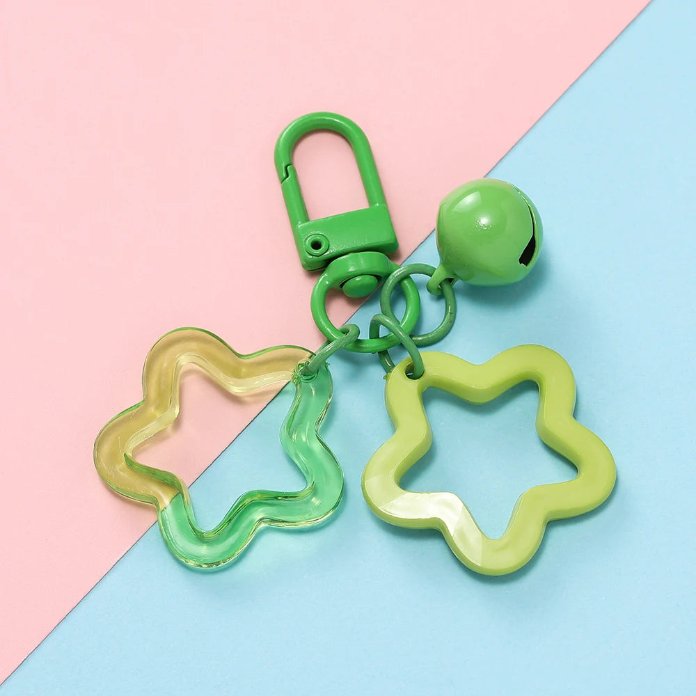 A green padlock charm and a yellow star charm pendant keychain displayed on a pink and blue background.