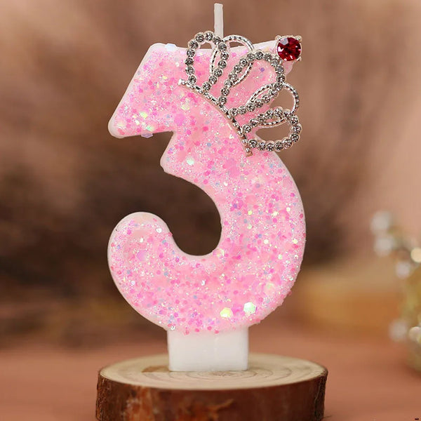 Pink glitter number three candle with a silver crown topper on a wooden base