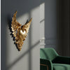 Gold ornate winged heart wall decor mounted on a gray wall with shadows