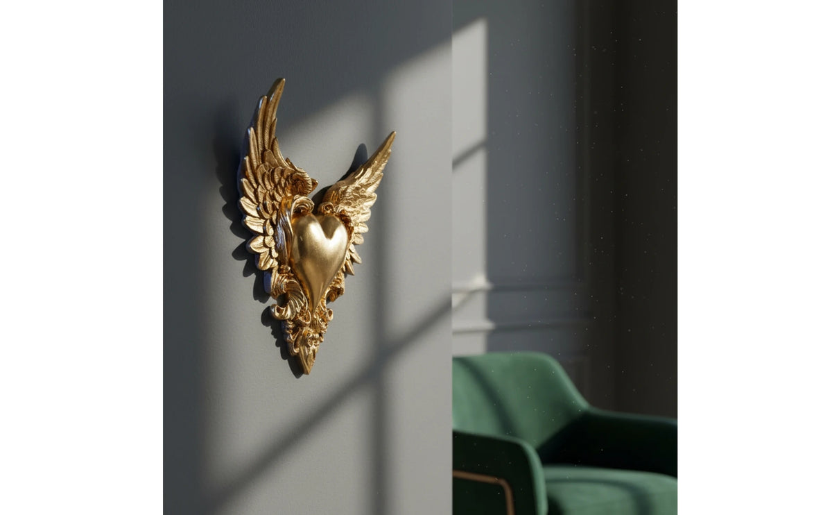 Gold ornate winged heart wall decor mounted on a gray wall with shadows
