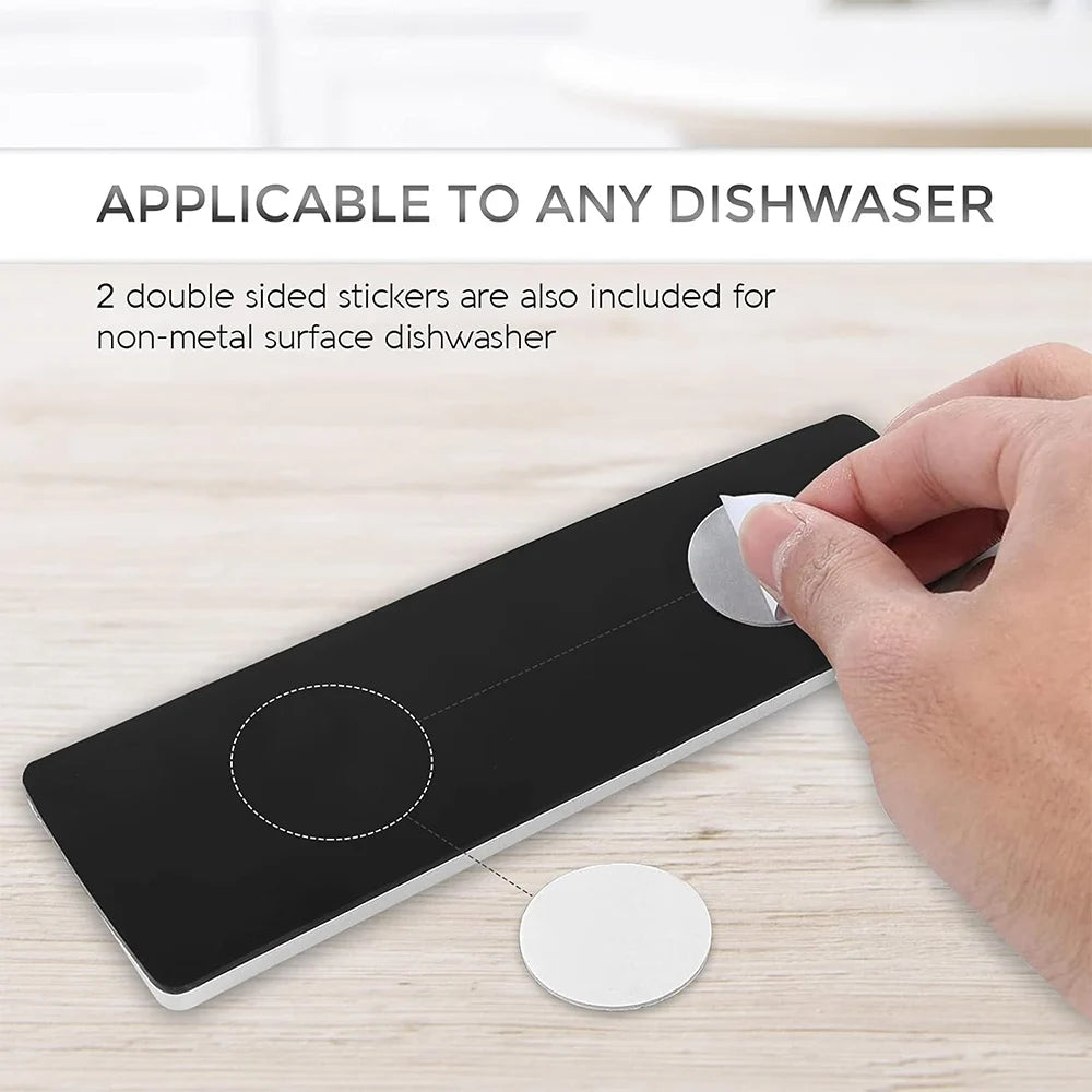 A hand is applying a double-sided sticker to a black magnet indicator for dishwasher cleaning.