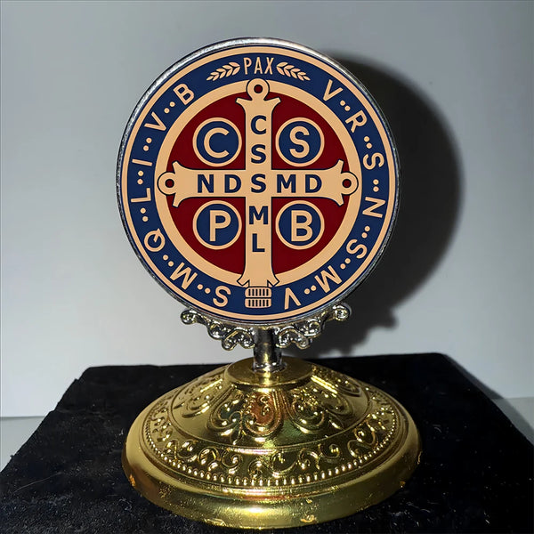 Runder Metallornament mit lateinischen Symbolen und religiöser Ikonographie auf goldener Basis.