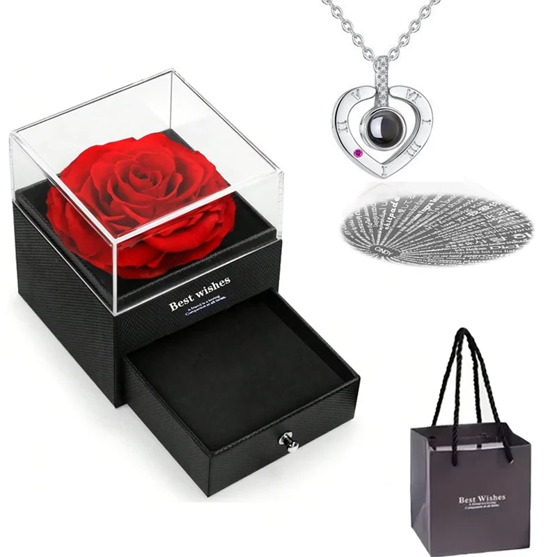 Un coffret cadeau avec une rose rouge conservée, un pendentif en cœur argenté et un disque argenté décoratif.
