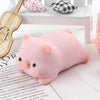 A pink mochi squishy toy shaped like a pig resting on a white wooden surface.